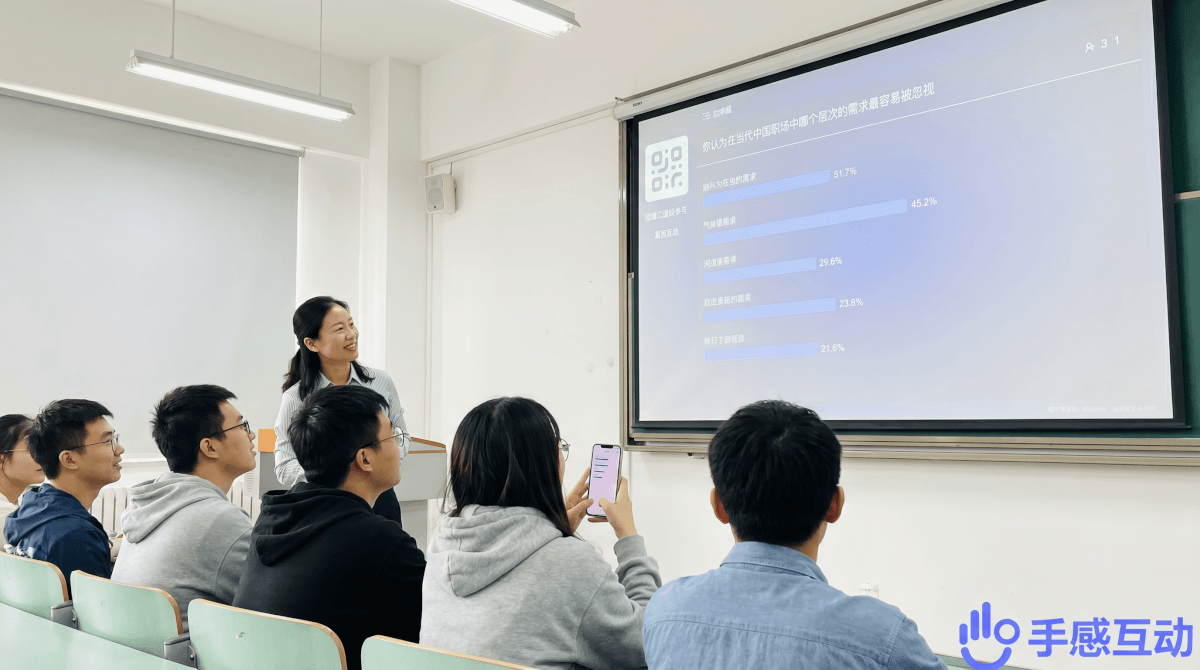 大学课堂上老师微笑看着大屏投票结果，学生们举着手机轻松参与互动