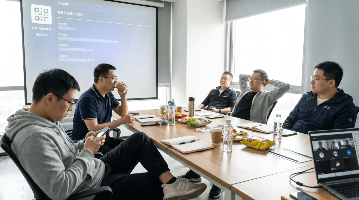 混合会议场景，会议室大屏显示实时投票结果，部分参会者通过手机参与互动